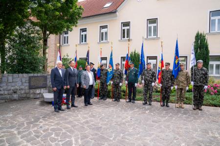 Polaganje cvetja in sveč k spomenikom pri občinski stavbi.